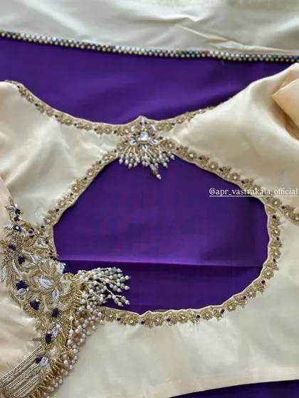 An off-white blouse with a keyhole back and peacock embroidery.