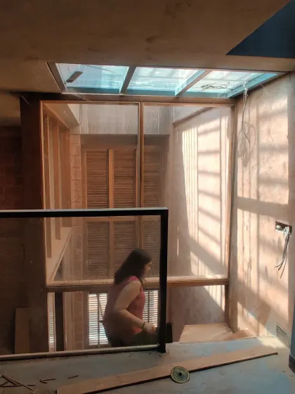 A view of a stairwell and skylight during construction, showing the raw wooden frames and the play of natural light.
