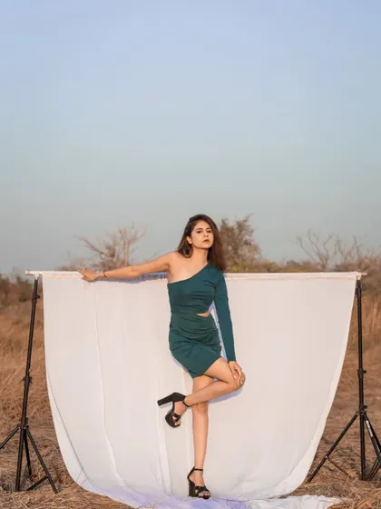 A full-length shot using a white backdrop in an outdoor setting. This creative setup makes the model and her green dress pop against the natural landscape.