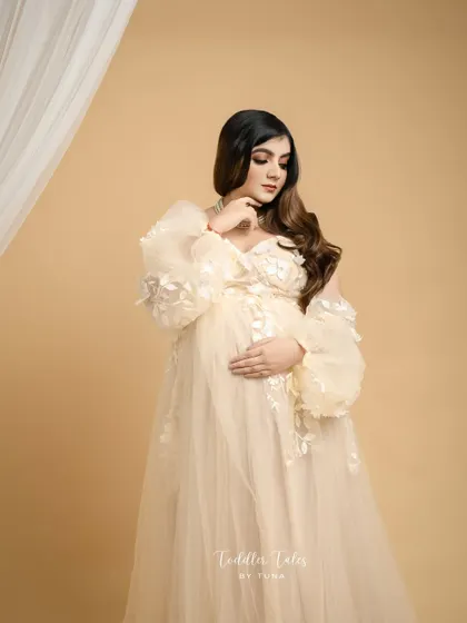 Gently touching your face or neck while looking down at your bump creates a soft, graceful line and a feeling of serene contemplation.