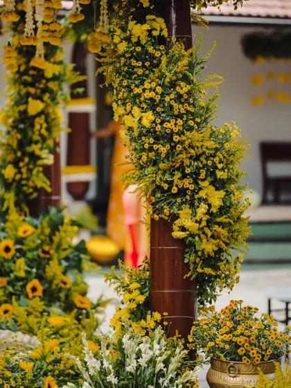 A close-up of the lush yellow floral arrangements wrapped around the mandap pillars, showcasing the density and vibrancy of the decor.