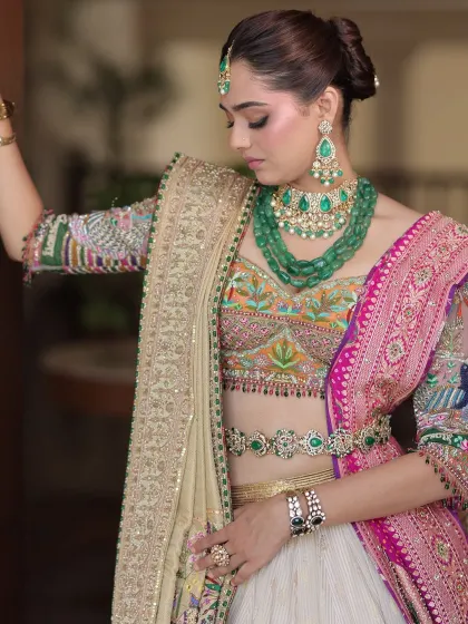 A detailed shot focusing on the intricate embroidery of the blouse and the layered emerald jewellery, highlighting the richness of the look.
