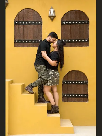 A romantic moment captured against a vibrant yellow wall. The architecture and colors add a unique, picturesque quality to this outdoor couple shoot.