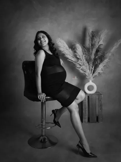 A confident and stylish black and white portrait. The pose with the bar stool and heels gives this maternity photo a chic and modern edge.