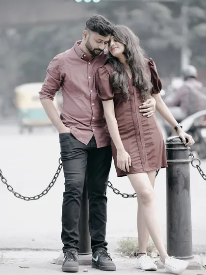 A romantic embrace on a city street, with the couple standing by a chain-linked bollard, creating a moody and intimate urban portrait.