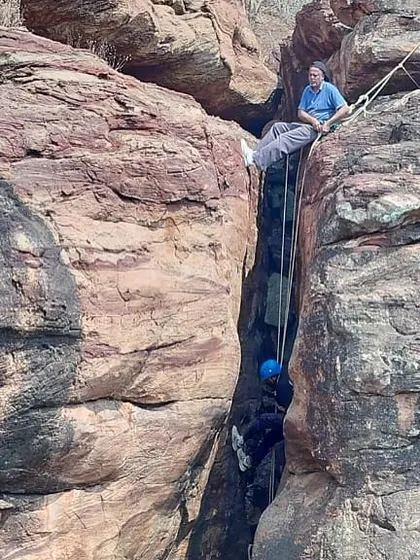 An instructor supervises a climber practicing chimneying techniques from above.