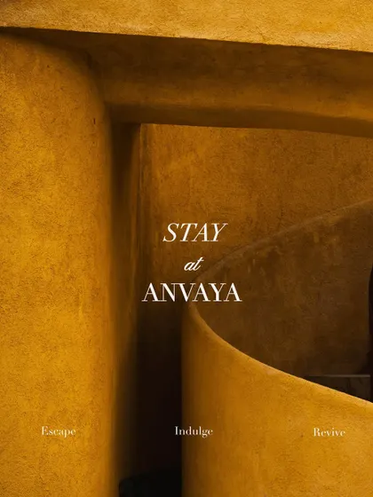 An invitation to "Stay at Anvaya," set against the backdrop of our unique spiral staircase. Escape, Indulge, Revive.