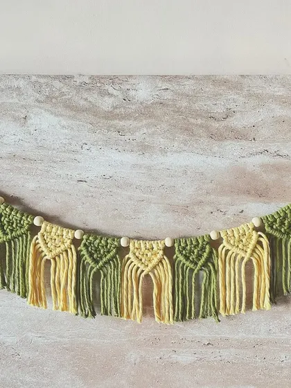 A beautiful macrame door toran or garland in shades of green and yellow. This is a wonderful, reusable decoration for festive occasions or to welcome guests to your home year-round.