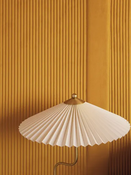 The 'Colonne' wallcovering in a warm ochre, perfectly complementing a pleated lampshade. This image highlights how texture can be layered to create a cohesive and sophisticated design story.