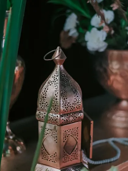 An ornate, perforated metal lantern adds a touch of Moroccan-inspired elegance and warm, patterned light to a decor vignette.