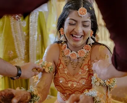 A close-up of the bride's infectious laughter during the Haldi ceremony, adorned with beautiful floral jewelry.