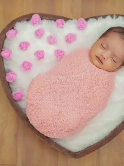 For my posed newborn sessions, I use a variety of props like this heart-shaped basket. I ensure your baby is safely and comfortably swaddled, creating a peaceful and adorable portrait.