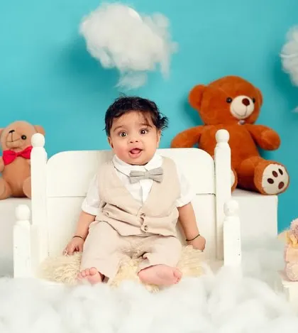 A classic portrait of a baby boy in a smart vest and bow tie. The fluffy clouds and teddy bears create a dreamy, playful atmosphere.