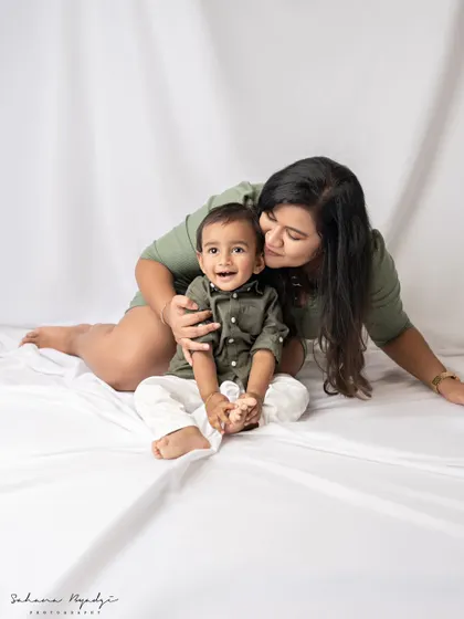 A mother and son share a quiet, loving moment. Her gentle kiss and his happy smile create a simple yet powerful image of their bond.