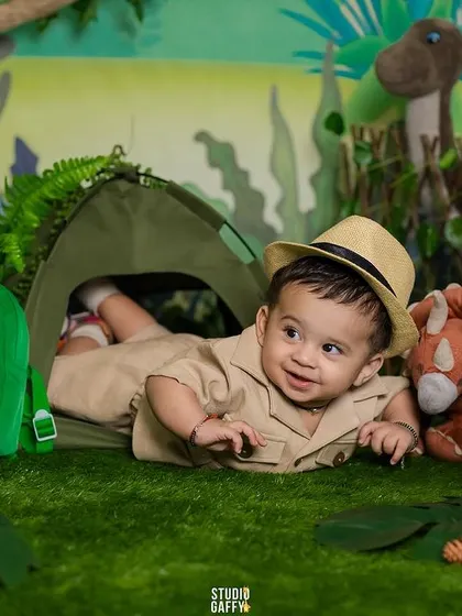 This six-month-old explorer is peeking out of his tent in the middle of a prehistoric jungle.