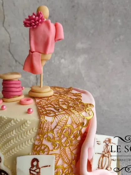 This cake celebrates a fashion designer's dream. The half-kg Milk Chocolate Truffle cake is decorated with a mannequin, a thread spool, sketches, and a beautiful gold lace fabric effect.