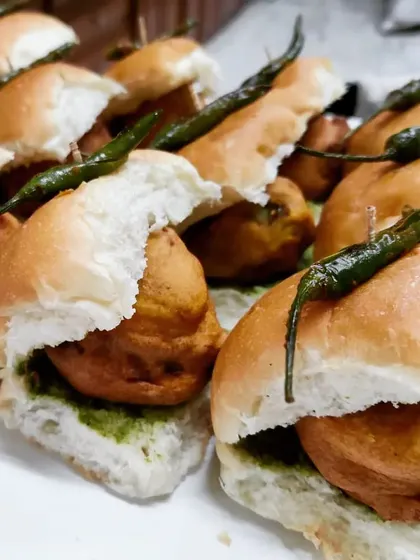 A detailed look at our homemade Vada Pav, with a spiced potato fritter tucked inside a soft pav bread, layered with green chutney and topped with a fried green chili.