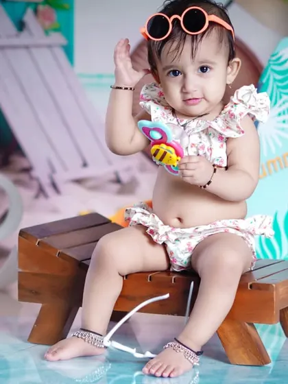 This little fashionista tries on her sunglasses, adding a cool and playful vibe to her beach photos.