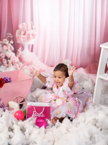 Pure joy in a Barbie dreamland. This little girl's excited expression is priceless as she plays among the pink props and fluffy clouds of her Barbie-themed session.
