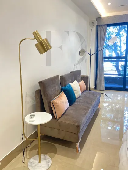 This sofa bed in a rich brown fabric is a perfect example of functional luxury. It's paired with a modern floor lamp that includes an integrated marble-topped side table, ideal for compact living spaces.