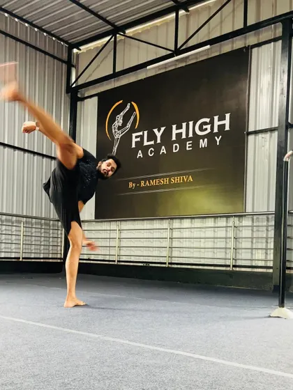 A student executes a high kick in front of the Fly High Academy banner. This powerful image captures the spirit of our training.