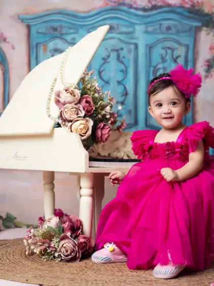 Such a joyful smile! A beautiful portrait of a one-year-old girl in a stunning pink dress.