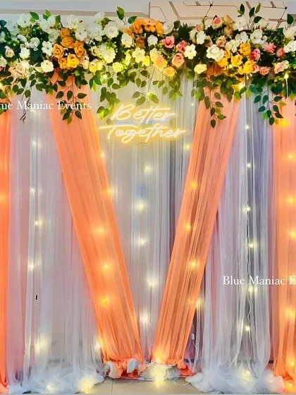 A full view of the peach and white 'Better Together' backdrop, showing the delicate draping and the warm glow of the fairy lights.