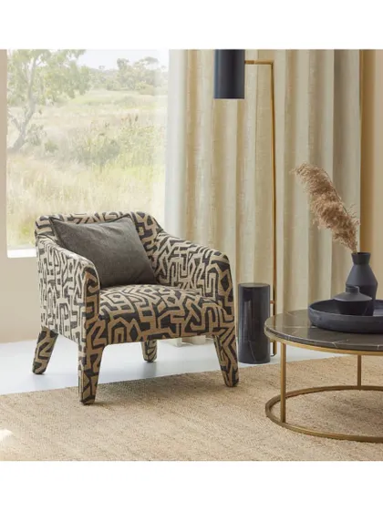 This armchair, upholstered in a bold geometric 'Hiraani' fabric, becomes the focal point of the room. I often suggest a single, statement piece of furniture to anchor a space and express a client's personality.