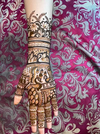 A beautiful arm design featuring a variety of traditional motifs. You can see peacocks, swans, and temple bells, all woven together with intricate patterns.