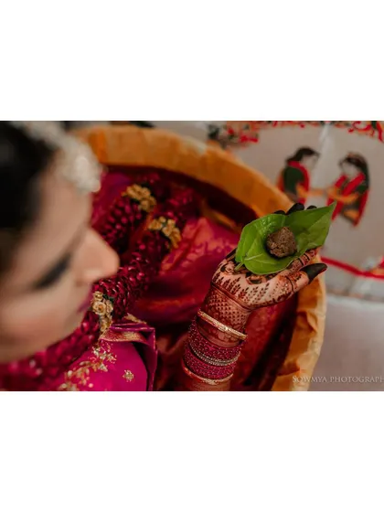 A close-up of a bride holding a betel leaf with areca nut, an important part of many South Indian rituals.