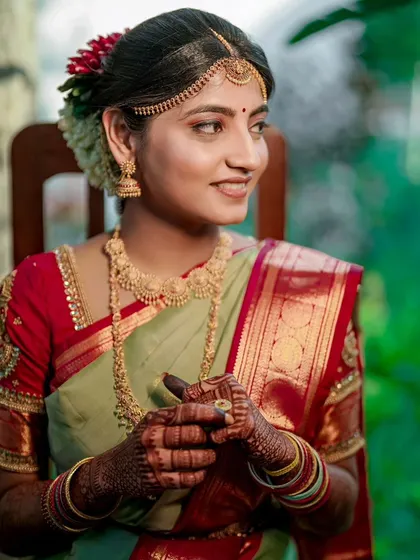 A classic bridal portrait, capturing the bride's elegance and the rich details of her silk saree and gold jewelry.