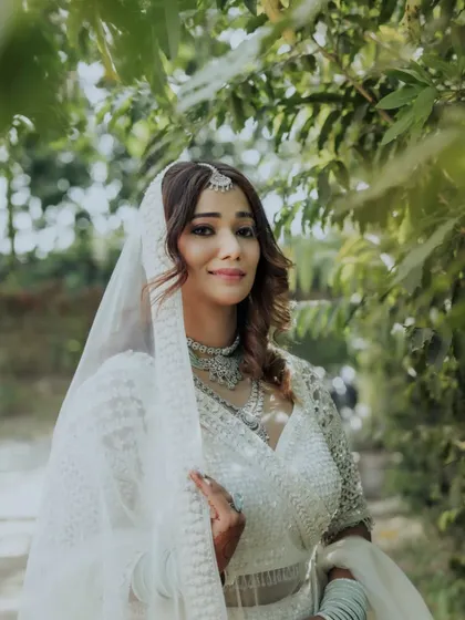 A lovely, smiling portrait of the bride, framed by the leaves of a tree, creating a natural and soft composition.
