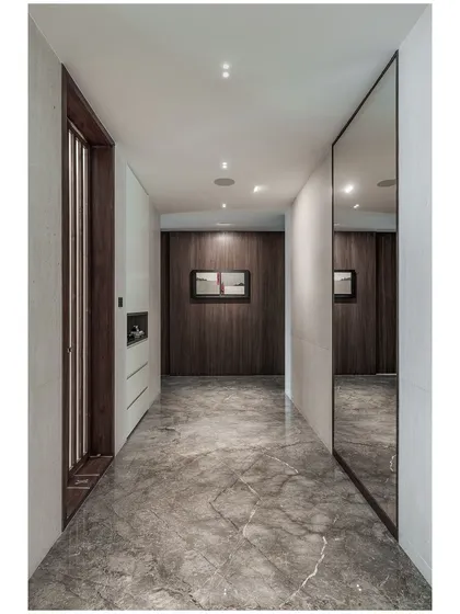 This shot emphasizes the clean lines and material contrast in the corridor. The interplay between the cool marble floor and the warm wood wall creates a balanced and sophisticated feel.