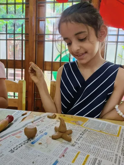 A girl carefully assembles her clay snowman, demonstrating precision and patience. Clay modelling is a wonderful way to build three-dimensional thinking skills.