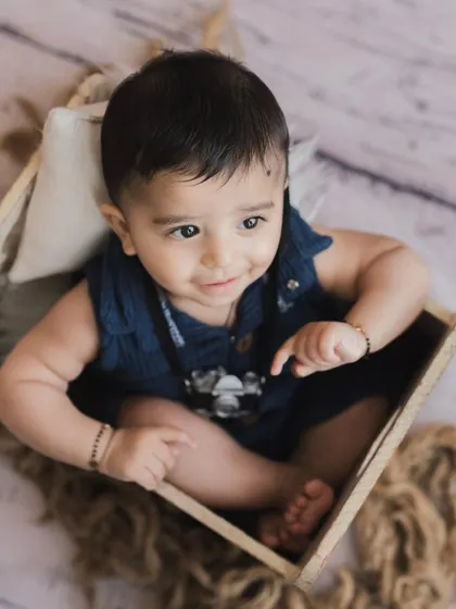 An overhead shot of a happy baby in a wooden box. We use different angles and props to create a variety of interesting and cute portraits.