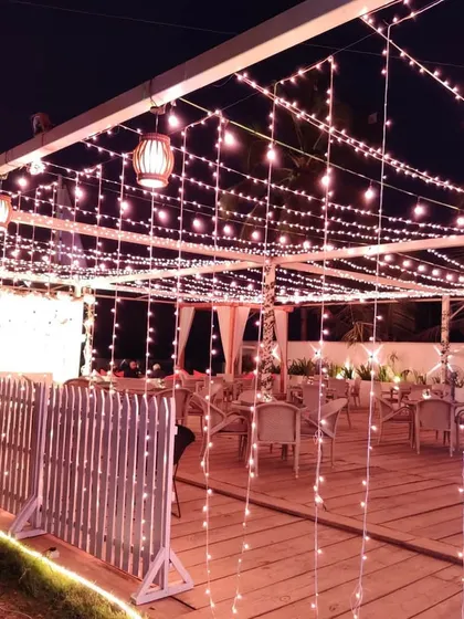 An intimate engagement party setup on a deck overlooking the ocean. We used a canopy of fairy lights and hanging lanterns to create a romantic and cozy atmosphere for the celebration.