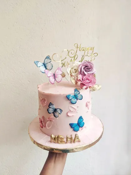 This soft pink ganache cake is adorned with a mix of colorful butterflies and fresh roses. It's a sweet and elegant design, perfect for birthdays of all ages.