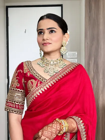 A timeless and elegant look. The makeup is clean and minimal, with a focus on flawless skin and a simple red bindi to complement the traditional attire.
