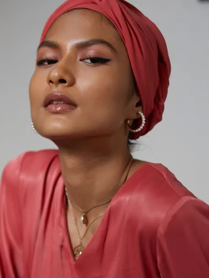 A modern and modest fashion portrait. The rich color of the outfit and turban, paired with a confident expression, creates a powerful and stylish image for the brand.