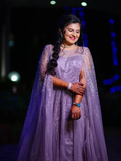 A stunning portrait of the bride at her reception. Her lavender gown with a sparkling cape looks magical against the dark background with blue lights.