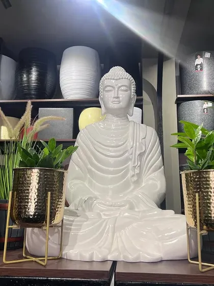 A serene corner in our store featuring a white fibre Buddha statue. It's flanked by two elegant golden metal planters, creating a peaceful and stylish display.