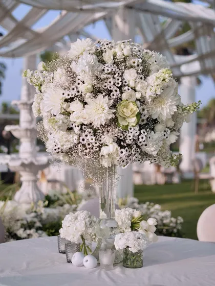 A close-up of one of the magnificent centerpieces, composed of white dahlias, roses, and baby's breath. The intricate texture and pure white color create a look of timeless sophistication.