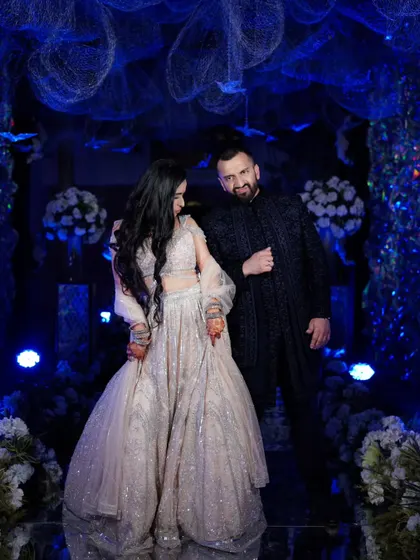 A playful moment between the couple, their poses reflecting their fun and dynamic relationship against the backdrop of the stunning blue-themed decor.