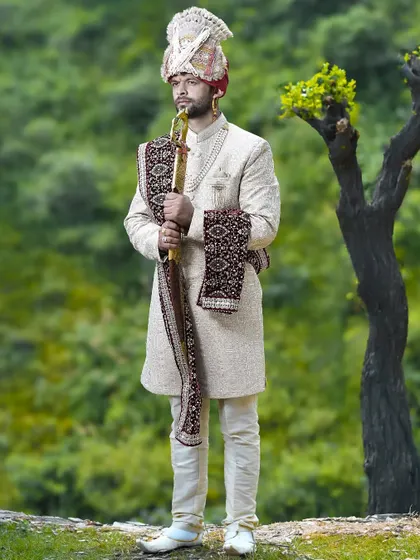 A full-length portrait of the groom with his ceremonial sword. This traditional pose against a natural backdrop creates a powerful and timeless image.