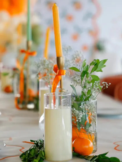 A close-up of the tablescape, showing how simple elements like oranges, greenery, and tall tapered candles can create a stunning, organic, and elegant look.