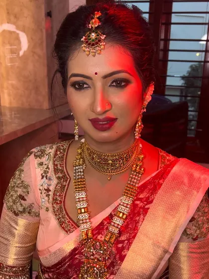 This bride is ready for her ceremony, showcasing a beautiful look with a bright pink lip that pops against her elegant saree. The makeup is designed to be long-lasting and picture-perfect.