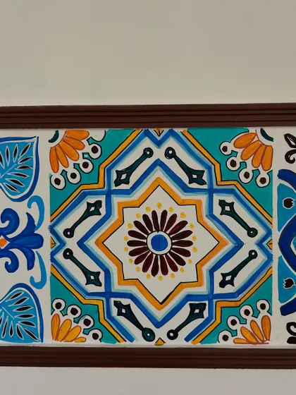 A detailed shot of one of the hand-painted Moroccan tiles. You can see the precise linework and color choices that give the illusion of real ceramic tiles, adding texture and character to the wall.