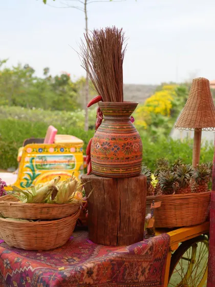A detail shot of a decor cart, featuring rustic elements like a painted vase, corn cobs, and pineapples.