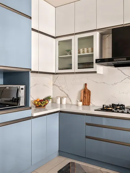 This compact L-shaped kitchen uses a beautiful powder blue and white color scheme. The marble-patterned backsplash adds a touch of luxury, and we've included a dedicated niche for the microwave to save counter space.