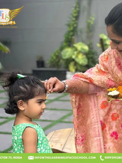 A teacher applies a tilak to a child's forehead. This simple, warm gesture is a beautiful part of our festive welcoming ceremony, making every child feel included.